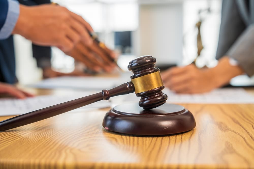 Business team and lawyer in formal suits meeting at a desk to discuss a contract and legal matters.